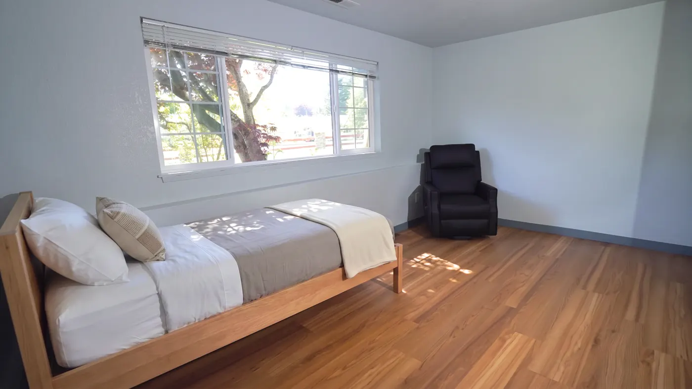 Bedroom with twin bed, recliner, and Japanese maple view