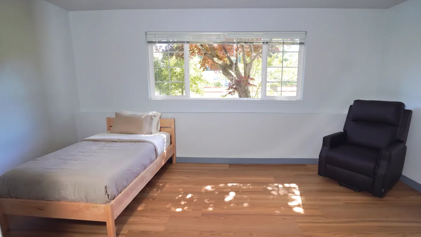 Light-filled bedroom with recliner and large windows