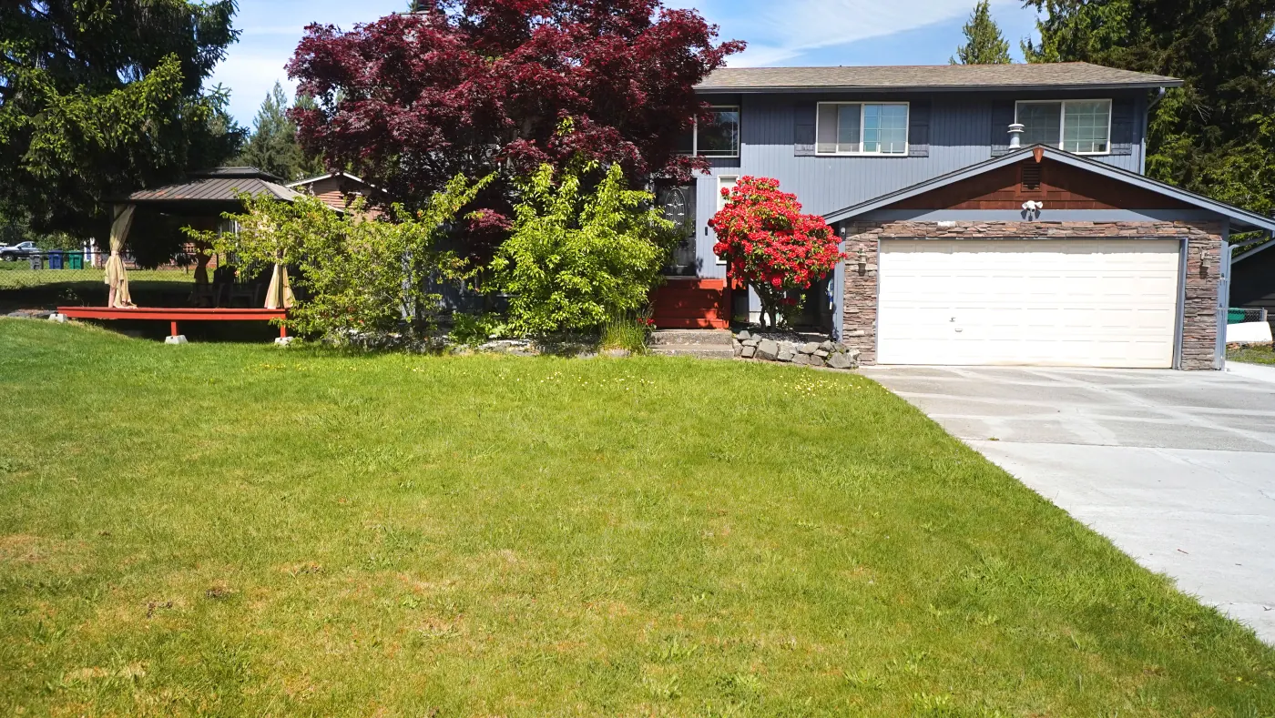 Front yard view of the home with green lawn and garden